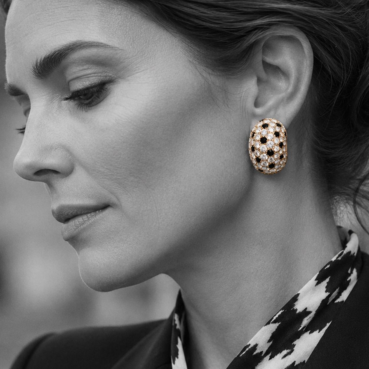 Een paar geelgouden oorclips, geheel pavé bezet met vele briljant geslepen diamanten en onyx, gesigneerd Van Cleef & Arpels, Parijs, ca. 1980.