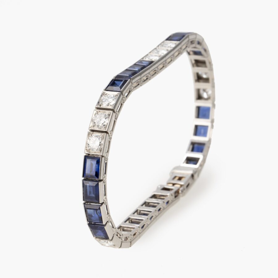 Een platina rivière armband bezet met saffieren en diamanten, vervaardig in 1955 en genummerd. Met certificaat van Oscar Heyman, New York.