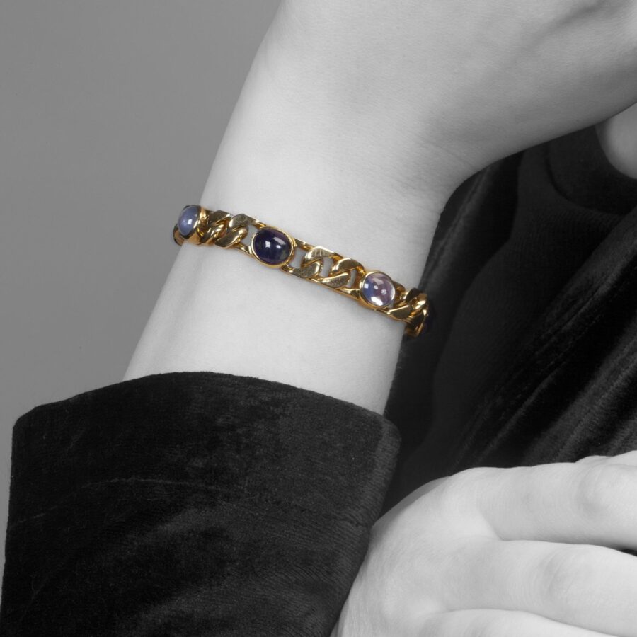 Een achttien karaat geelgouden gourmet schakelarmband bezet met 6 ovale cabochon geslepen blauwe saffieren in gladomzettingen. Gesigneerd Bvlgari, ca1980.