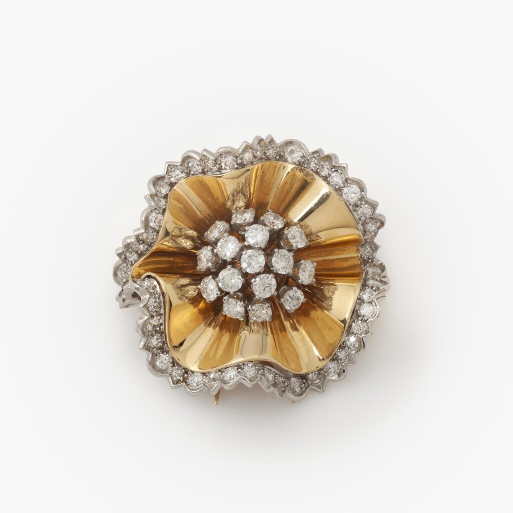Een achttien karaat geelgoud en platina broche in de vorm van een rozet, deels bezet met diamanten. Gesigneerd Van Cleef & Arpels, Parijs,1947.