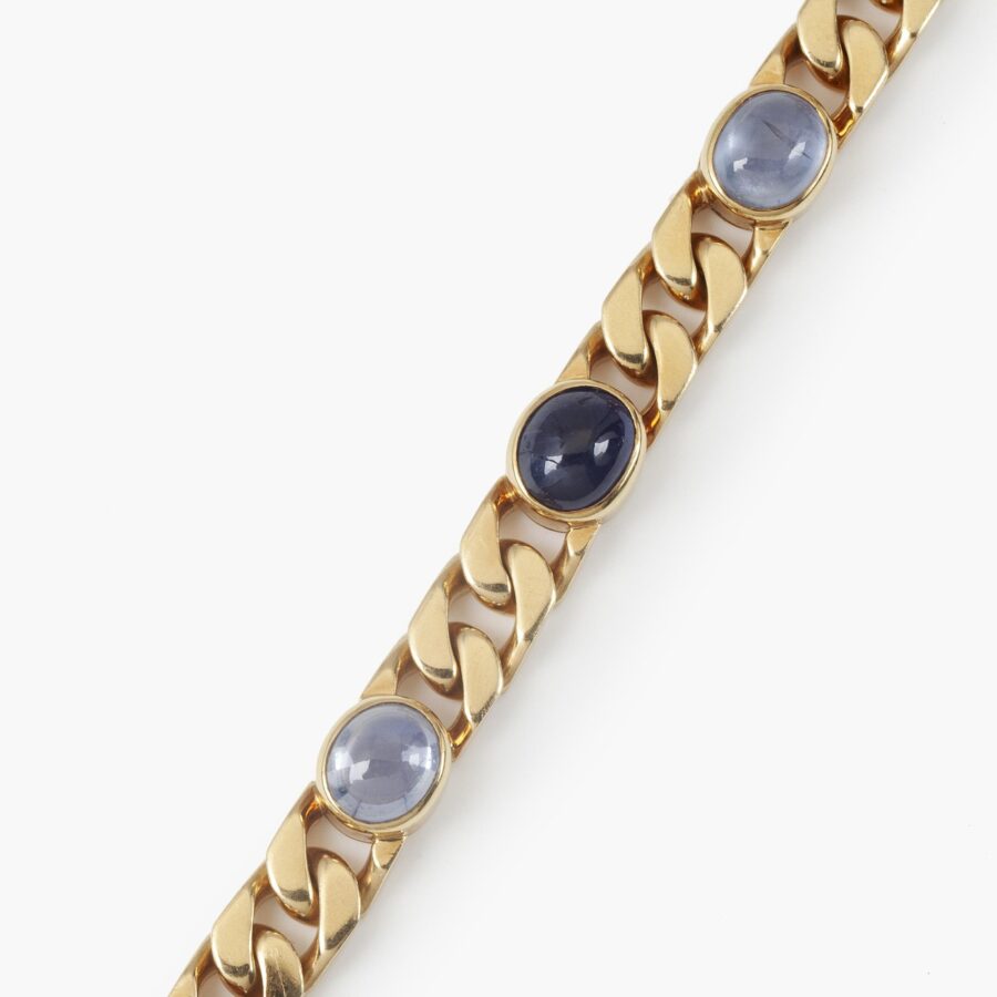 Een achttien karaat geelgouden gourmet schakelarmband bezet met 6 ovale cabochon geslepen blauwe saffieren in gladomzettingen. Gesigneerd Bvlgari, ca1980.