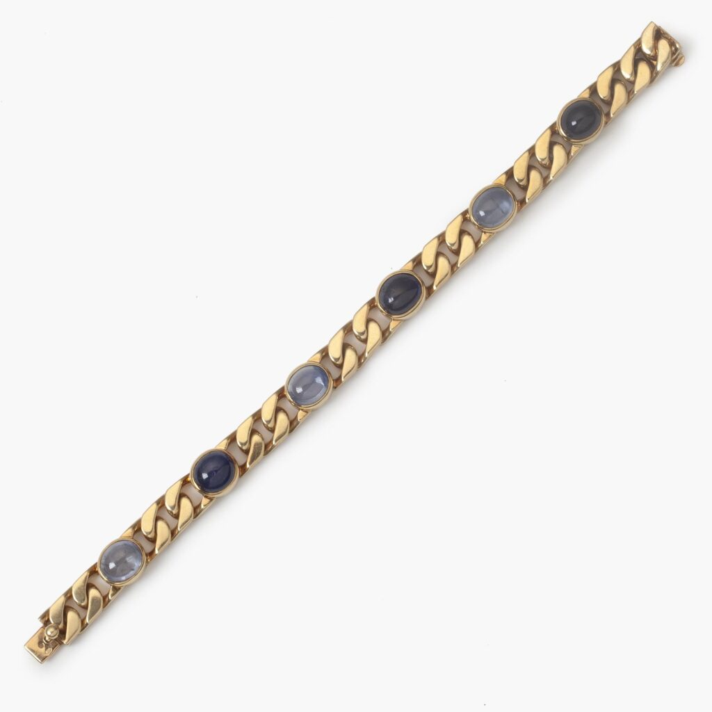 Een achttien karaat geelgouden gourmet schakelarmband bezet met 6 ovale cabochon geslepen blauwe saffieren in gladomzettingen. Gesigneerd Bvlgari, ca1980.