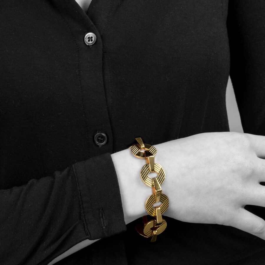 Een achttien karaat geelgouden armband bestaande uit ronde platte en driehoekige schakels. Gesigneerd Cartier, Londen. Gedateerd 1959