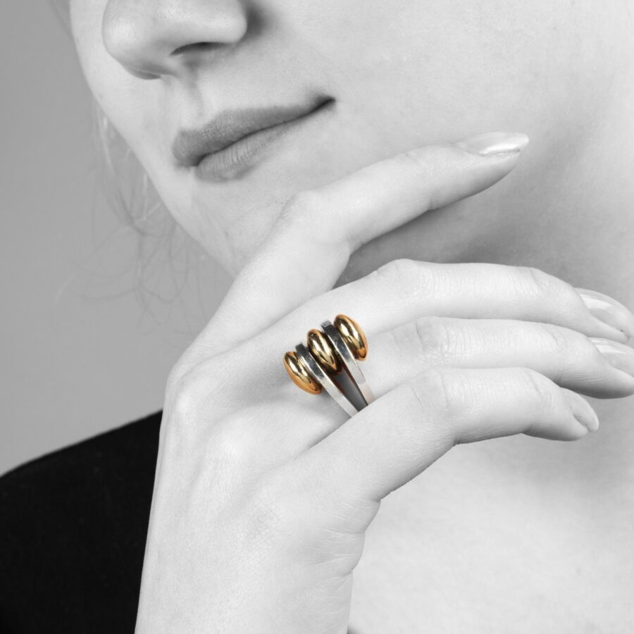 Een eerste gehalte zilveren ring met drie discusvormige veertien karaat geelgouden knoppen. Gesigneerd Pierre Cardin, vervaardigd omstreeks 1965.