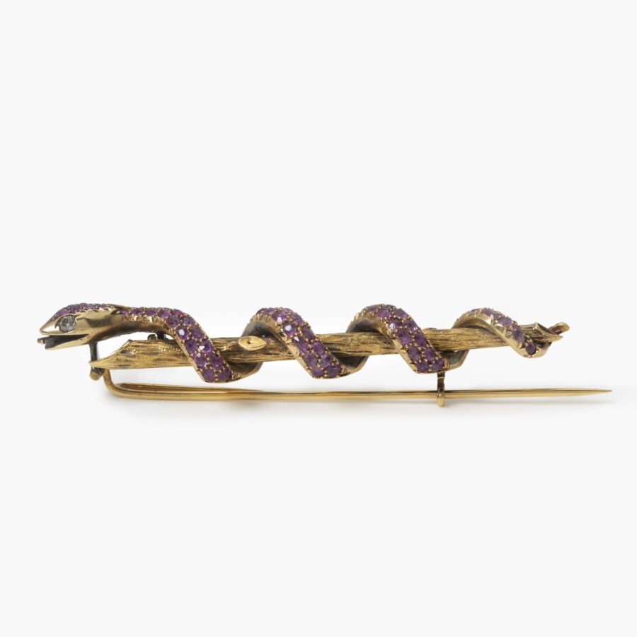 Een achttien karaat geelgouden broche in de vorm van een slang die zich rond een tak slingert, bezet met robijnen en twee diamanten. Nederland, ca 1890.