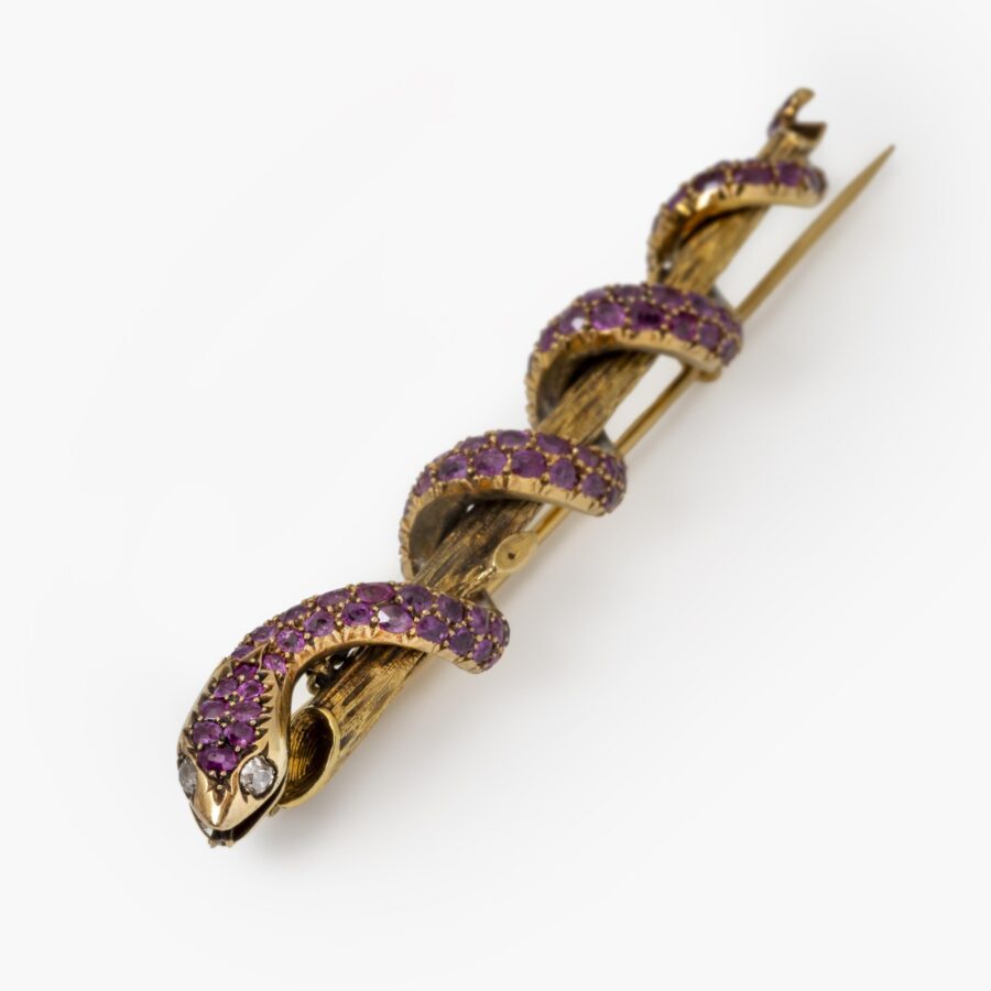 Een achttien karaat geelgouden broche in de vorm van een slang die zich rond een tak slingert, bezet met robijnen en twee diamanten. Nederland, ca 1890.