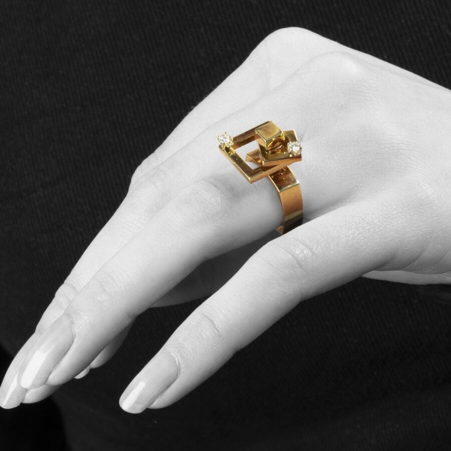 Een veertien karaat geelgouden kinetische ring bestaande uit twee draaiende vierkanten, elk bezet met een diamant. Gesigneerd N. Teufel, USA, 1972.