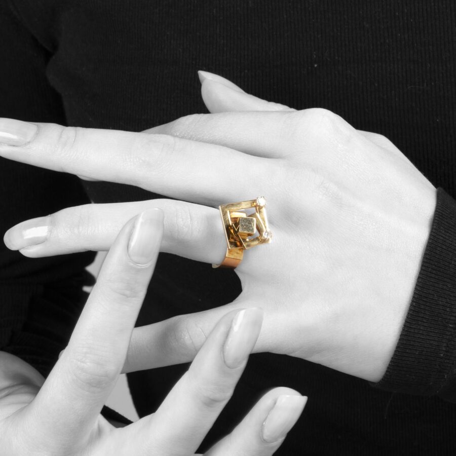 Een veertien karaat geelgouden kinetische ring bestaande uit twee draaiende vierkanten, elk bezet met een diamant. Gesigneerd N. Teufel, USA, 1972.