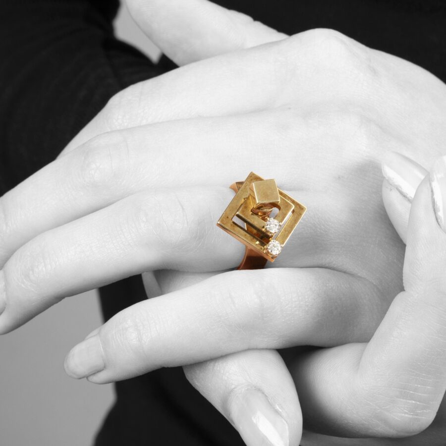 Een veertien karaat geelgouden kinetische ring bestaande uit twee draaiende vierkanten, elk bezet met een diamant. Gesigneerd N. Teufel, USA, 1972.