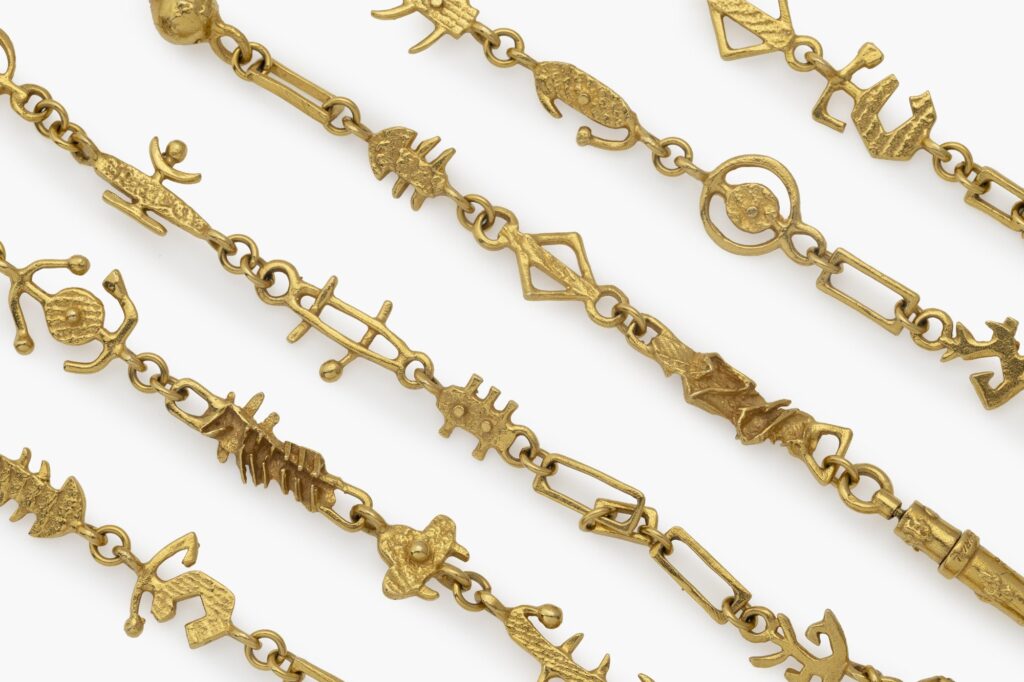 Een achttien karaat geelgouden sautoir van geschakelde abstracte motieven, alles met organische textuur. Gesigneerd A. Pomodoro vervaardigd ca 1981.