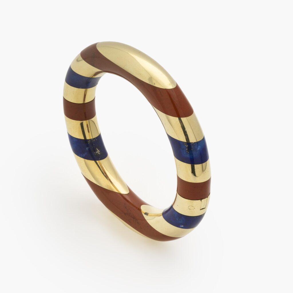 Een achttien karaat geelgouden stijve armband met gesneden lapis lazuli afgewisseld met banden van rode jaspis. Gesigneerd Tiffany & Co., omstreeks 1978.