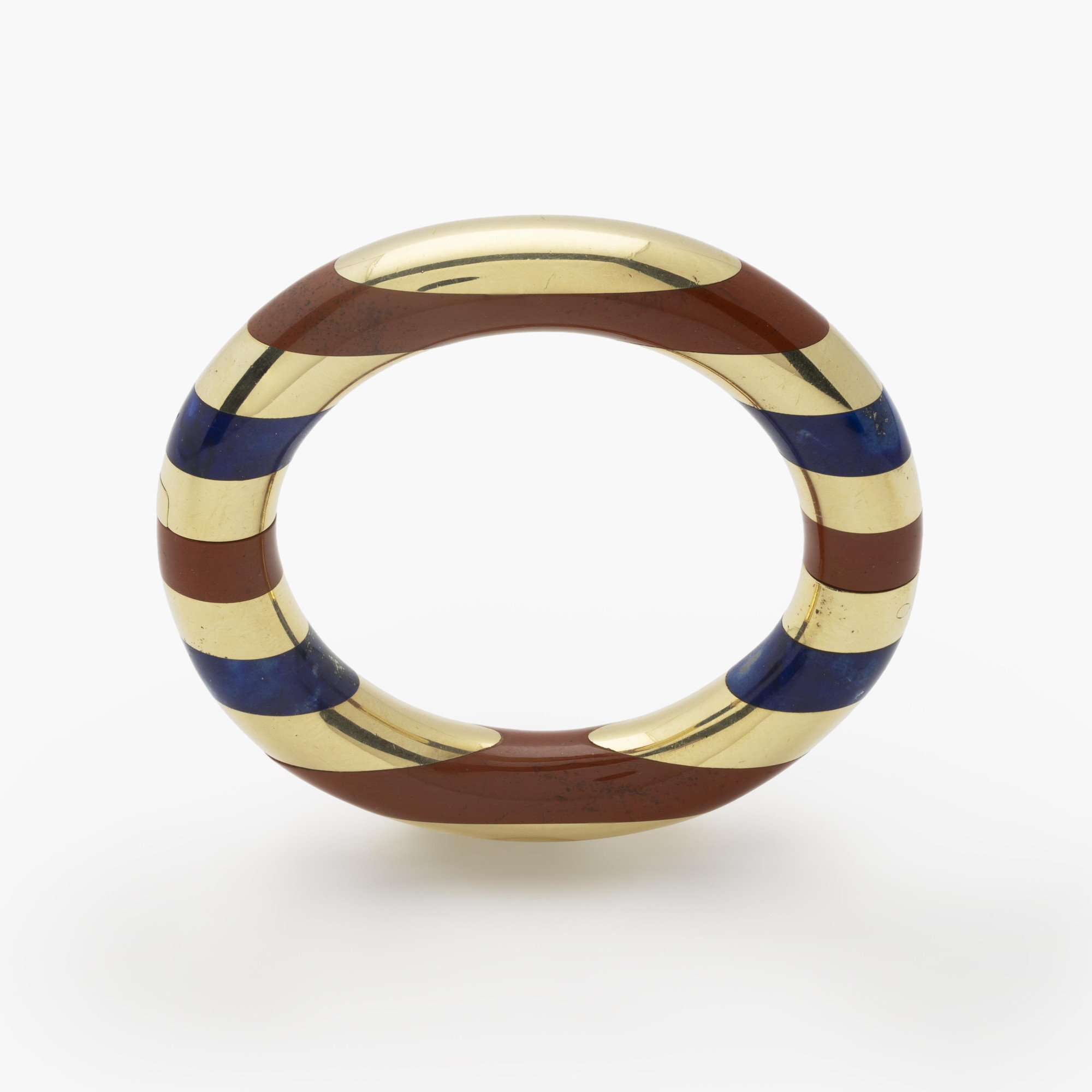 Een achttien karaat geelgouden stijve armband met gesneden lapis lazuli afgewisseld met banden van rode jaspis. Gesigneerd Tiffany & Co., omstreeks 1978.