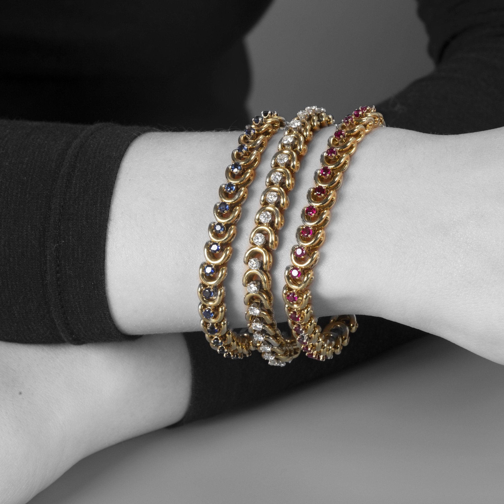 Een set van drie gelijke achttien karaat geelgouden armbanden; bezet met saffier, robijn en diamant. Van Cleef & Arpels, New York, in origineel etui.