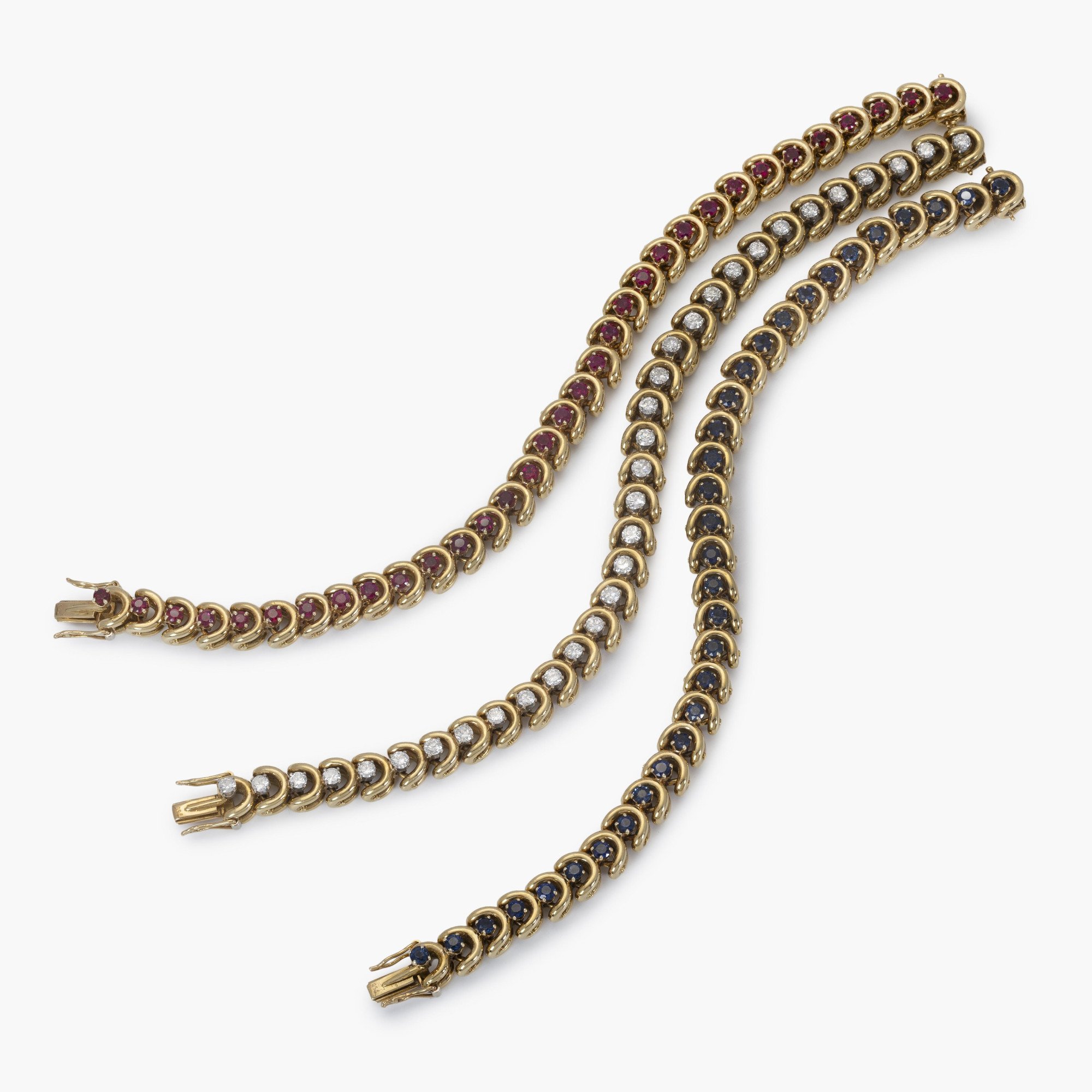 Een set van drie gelijke achttien karaat geelgouden armbanden; bezet met saffier, robijn en diamant. Van Cleef & Arpels, New York, in origineel etui.