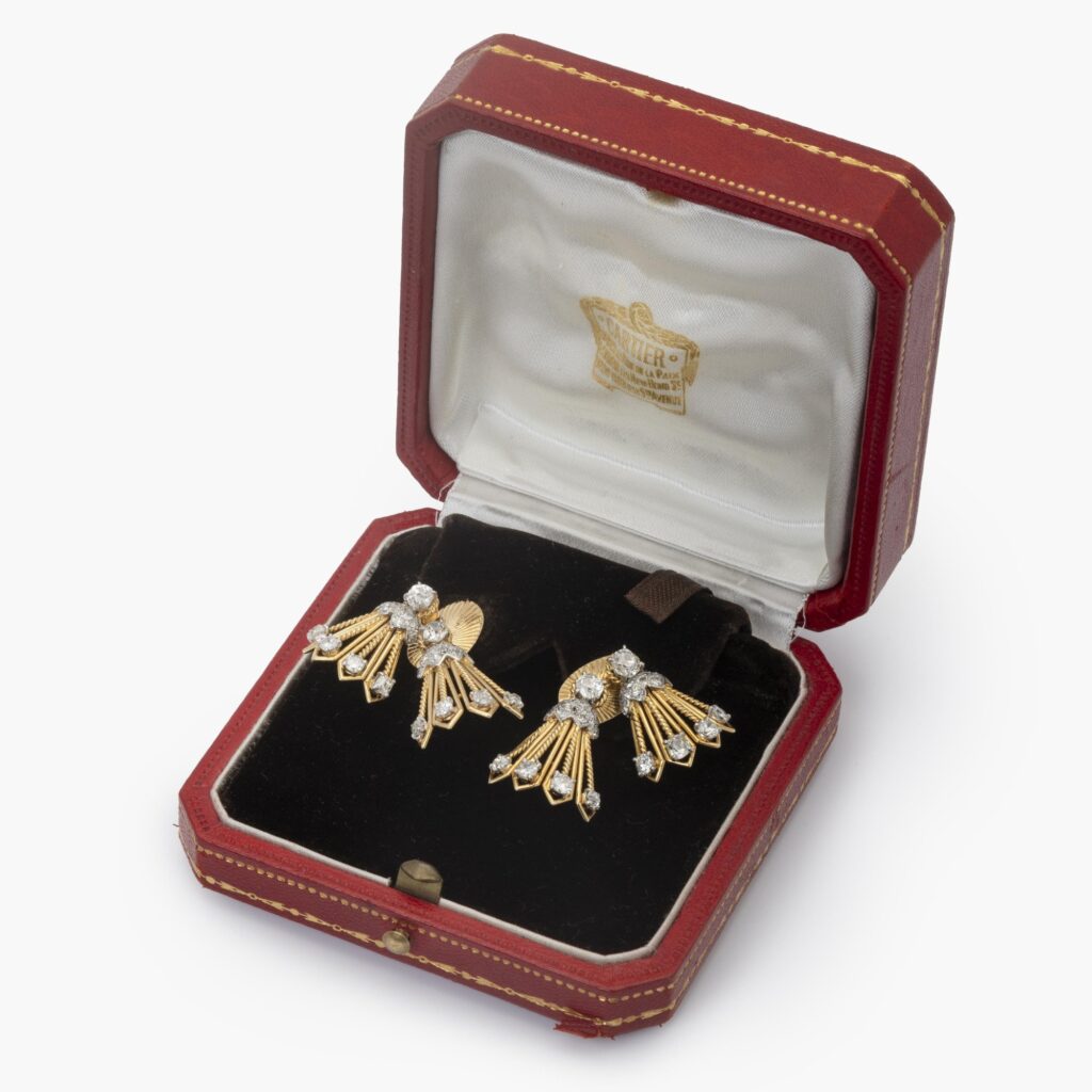Een paar achttien karaat geelgoud en platina oorbellen deels bezet met diamanten. Gesigneerd Cartier, vervaardigd in Parijs, ca 1950, in origineel etui.