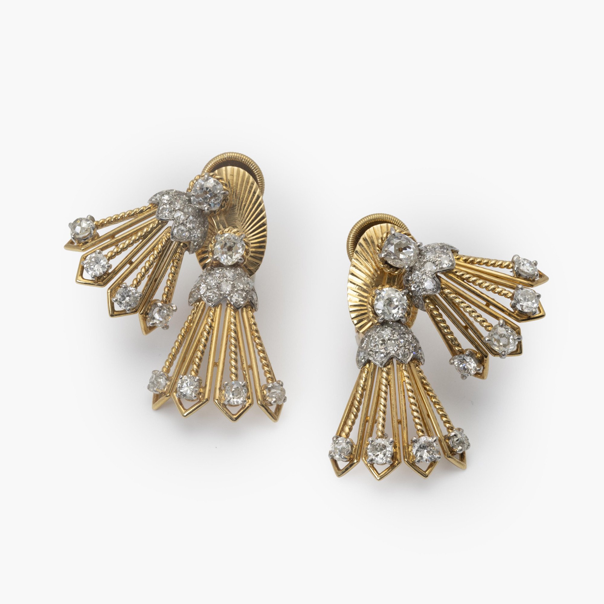 Een paar achttien karaat geelgoud en platina oorbellen deels bezet met diamanten. Gesigneerd Cartier, vervaardigd in Parijs, ca 1950, in origineel etui.
