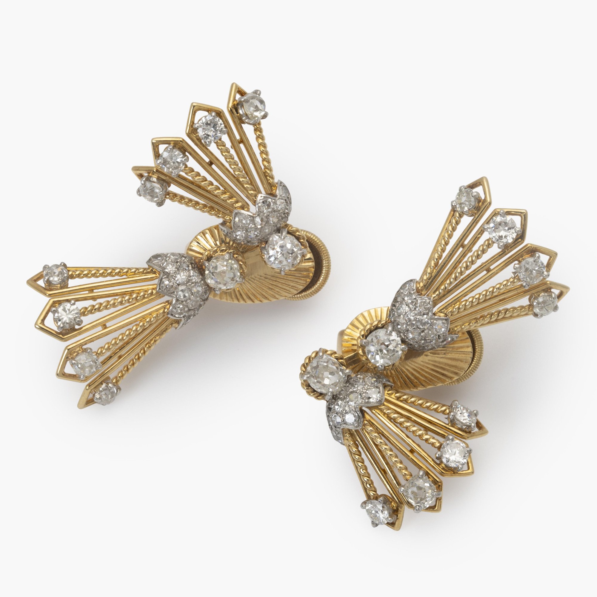 Een paar achttien karaat geelgoud en platina oorbellen deels bezet met diamanten. Gesigneerd Cartier, vervaardigd in Parijs, ca 1950, in origineel etui.