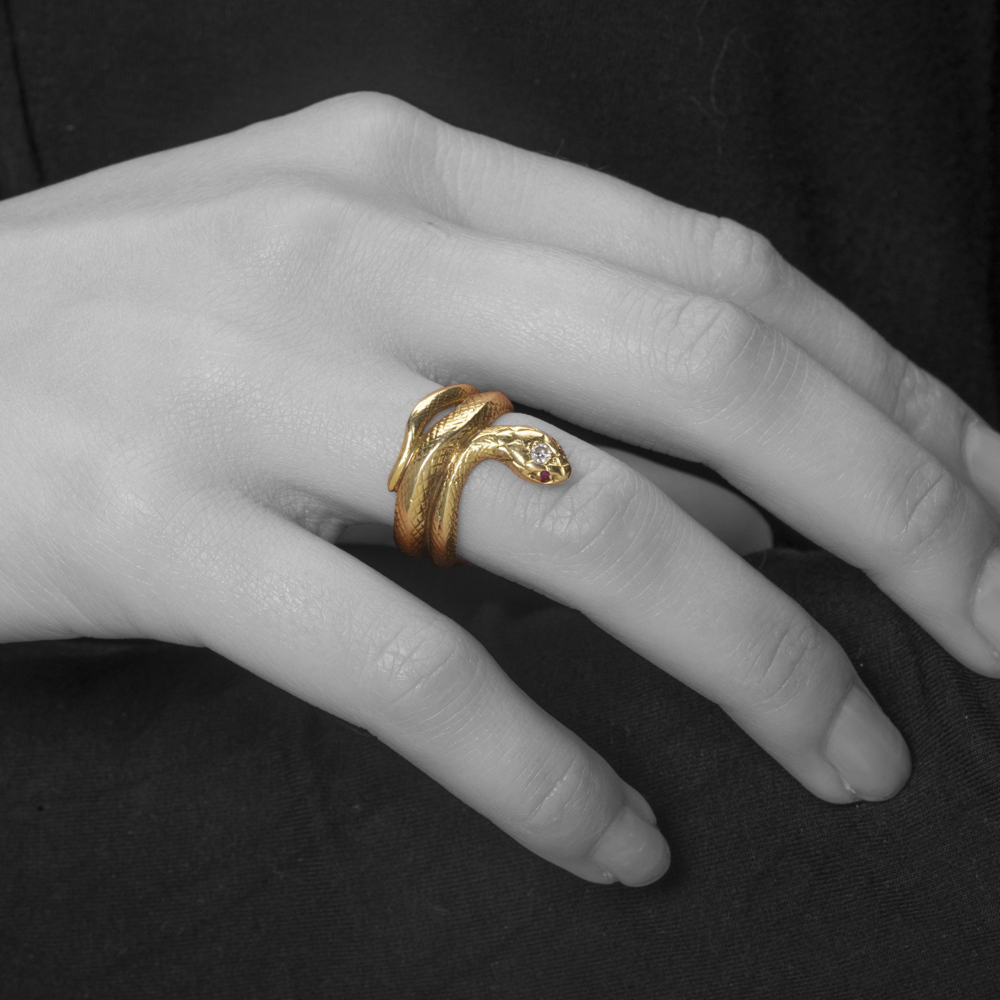Een achttien karaat geelgouden ring in de vorm van een slang; de kop bezet met een briljant geslepen diamant en twee robijnen als ogen.