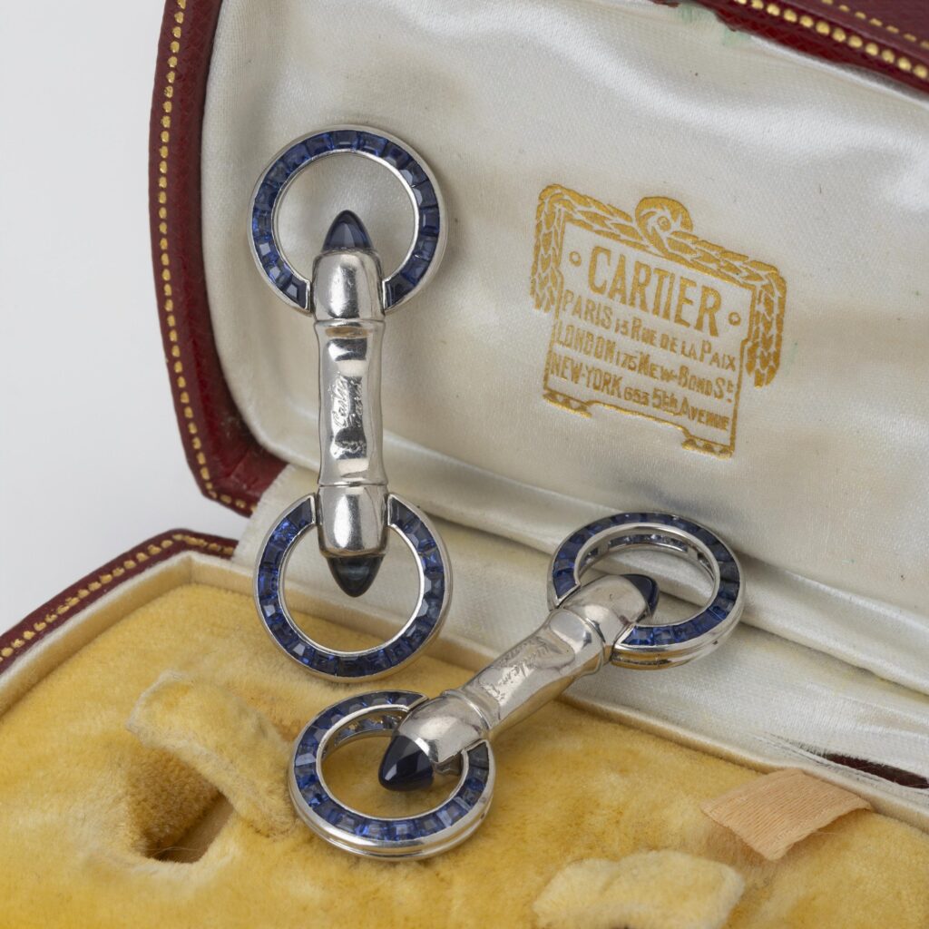 Een paar platina Art Deco manchetknopen bezet met saffieren en diamanten. Gesigneerd Cartier Paris en genummerd. Vervaardigd ca 1925. In origineel etui.