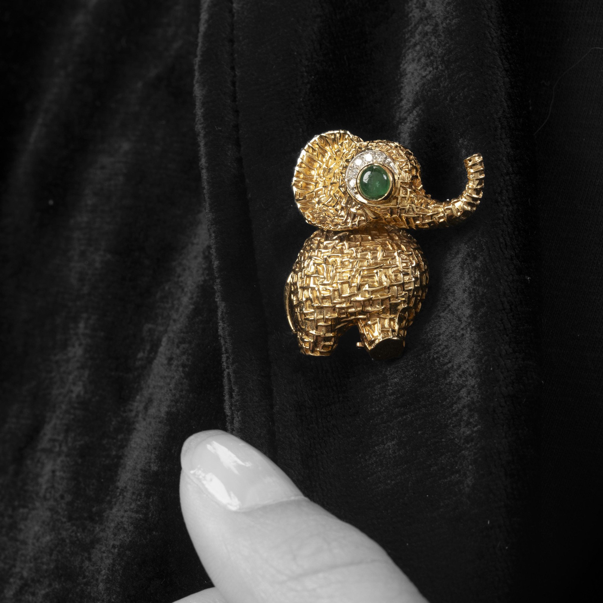 Een achttien karaat geelgouden broche in de vorm van een olifant, het oog bezet met smaragd en diamant. Gesigneerd Van Cleef & Arpels, Parijs, ca 1970.