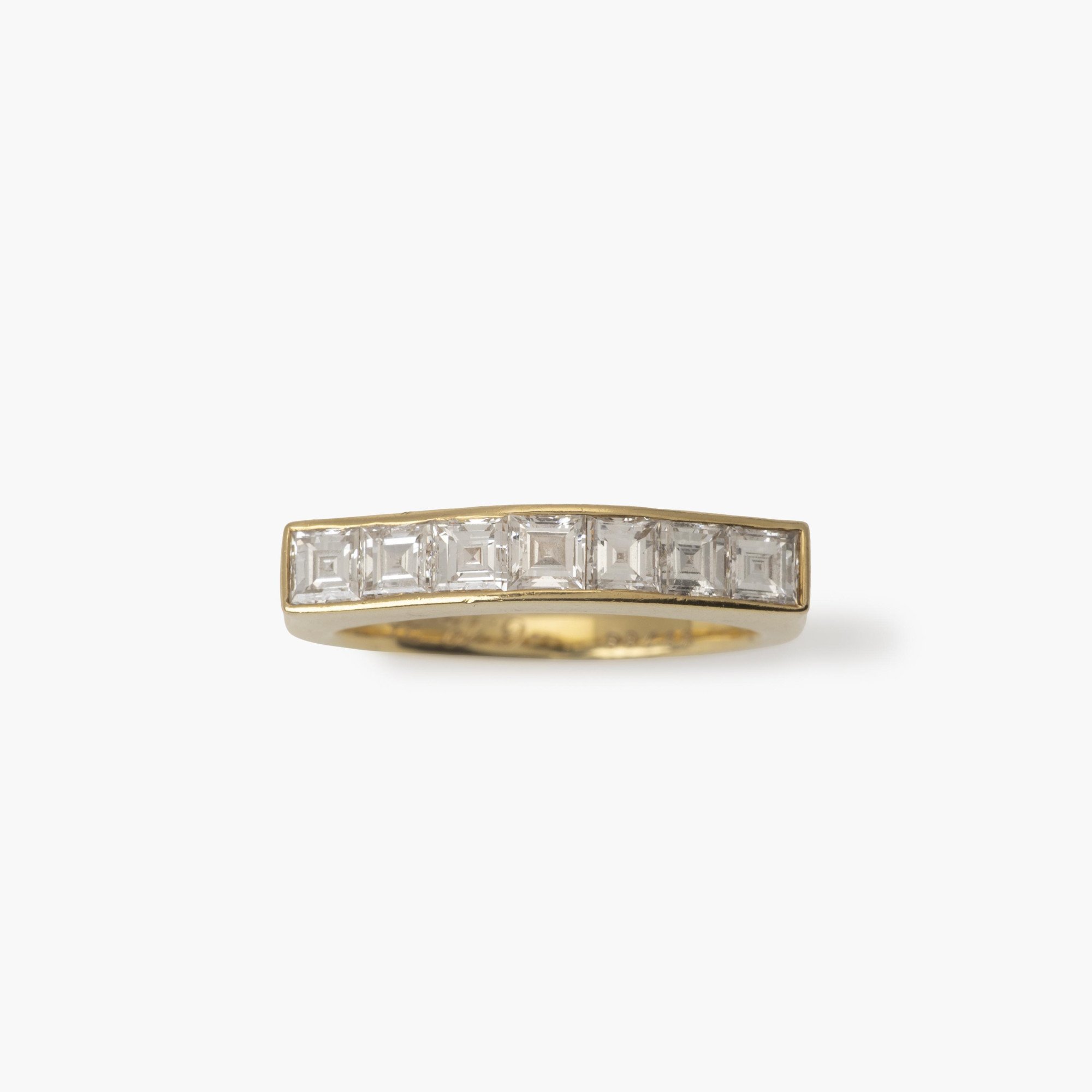 Een achttien karaat geelgouden rechte rijring, in railzetting bezet met zeven carré geslepen diamanten. Gesigneerd Cartier Paris en genummerd.