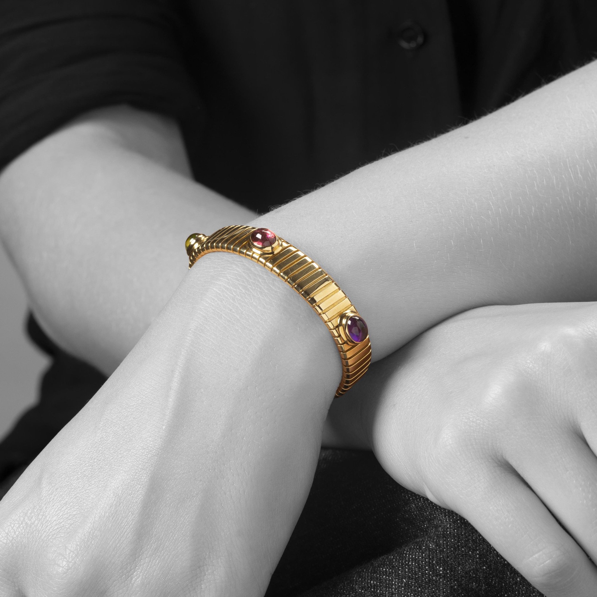 Een achttien karaat geelgouden rechte ‘Tubogas’ span armband, bezet met amethist, toermalijn en peridot. Gesigneerd Bvlgari, Italië, omstreeks 1995.